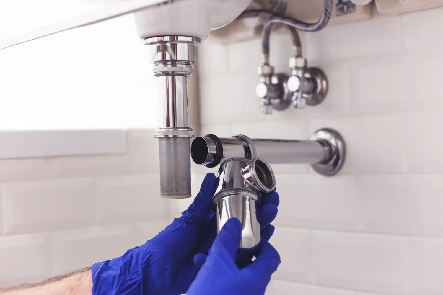 Klempner repariert und wartet Chromsiphon unter dem Waschbecken. Klempner bei der Arbeit im Badezimmer, Klempnerarbeiten montieren und installieren Konzept