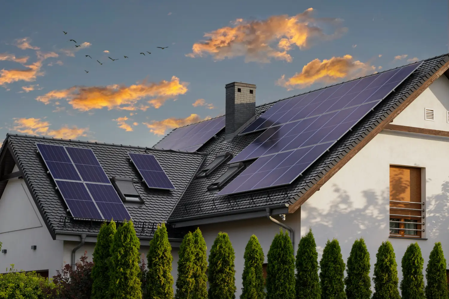 Modernes Haus mit blauen Solarmodulen auf dem Dach. Tagesende, Sonnenuntergang. Idyllische Atmosphäre.