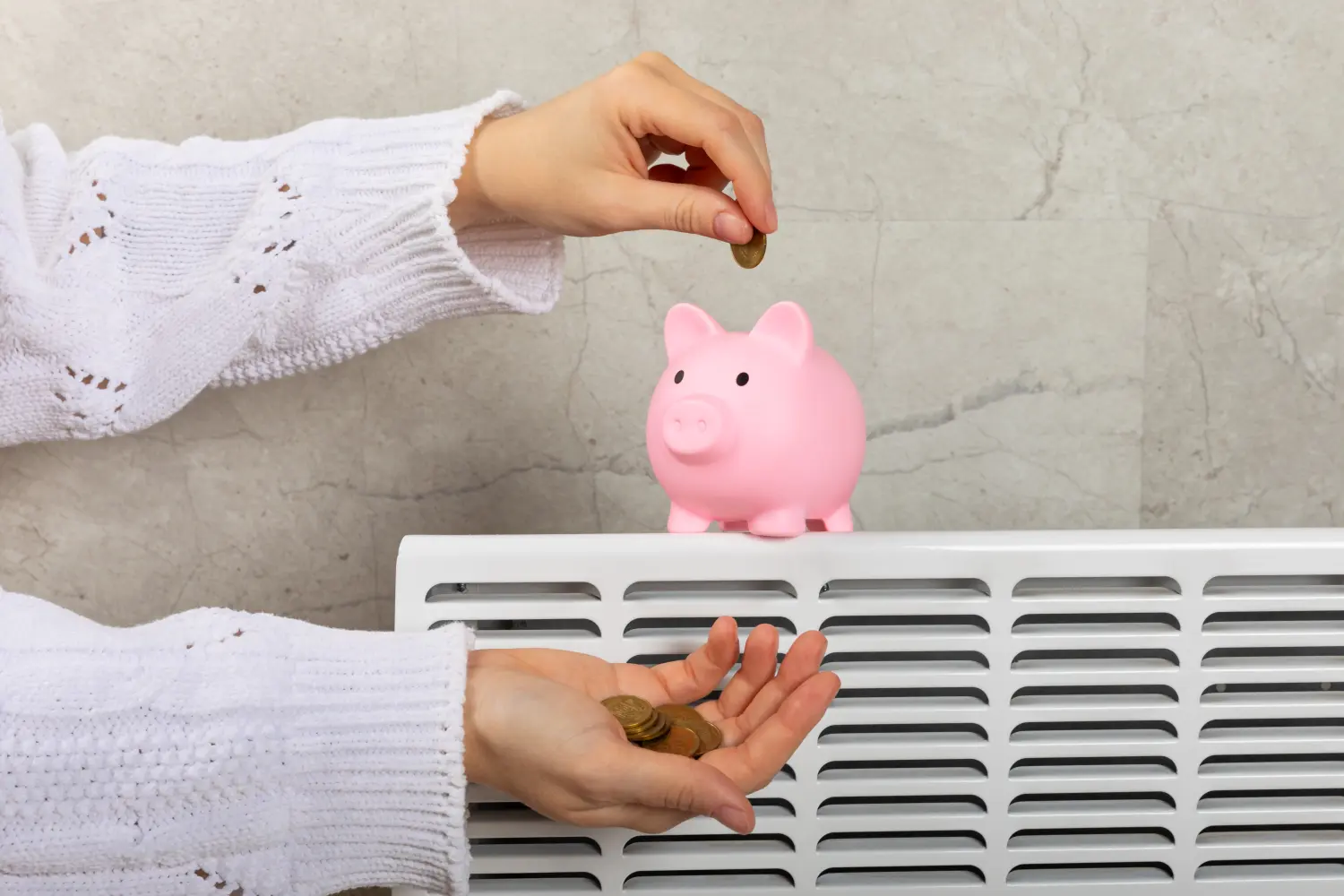 Frau legt Geld in Sparschwein auf Heizkörper mit Temperaturregler auf grauem Hintergrund. Heizsaison. Konzept teurer Heizkosten und steigender Energiekosten für die kalte Wintersaison.
